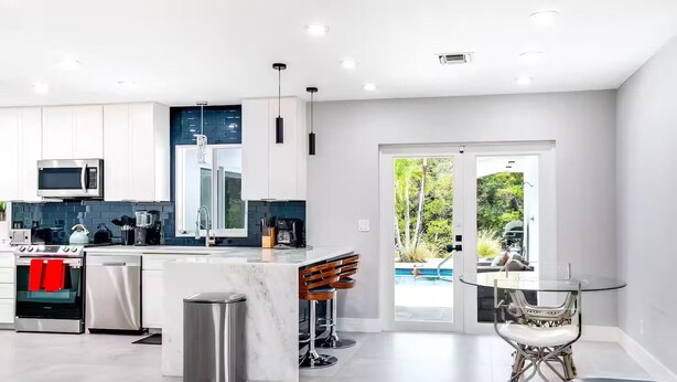 Een moderne keuken met witte kasten, roestvrijstalen apparatuur en een marmeren eiland.