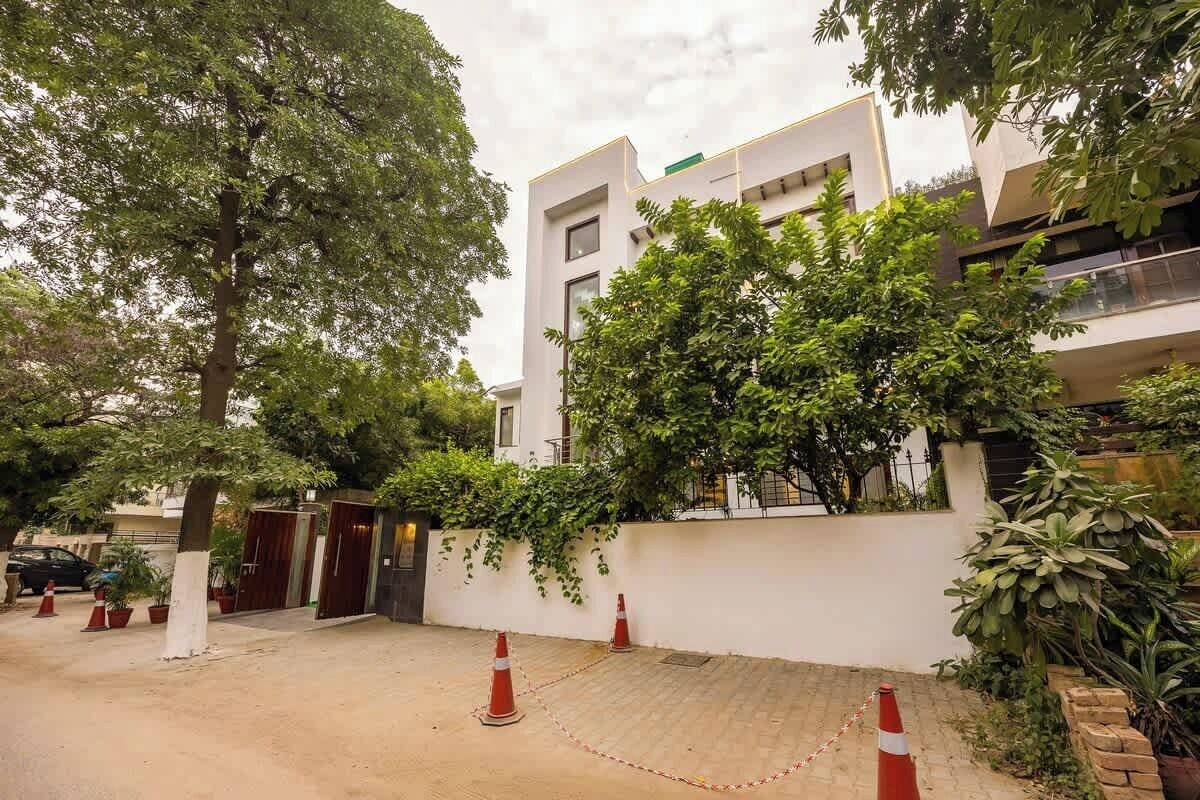 A modern building with a white facade, a gated entrance, and a paved driveway.