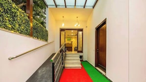 A staircase with a red carpet, a handrail, and a green carpeted area leading to a door.