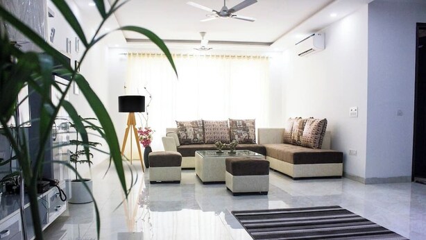 A modern living room with a sofa set, a coffee table, and a floor lamp. - Parfait Street 3Bhk Service Apartment Near Fortis (Gurugram)
