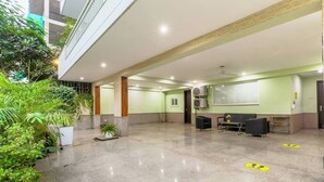 A spacious indoor area with a polished floor, seating arrangements, and greenery. - Parfait Street 3Bhk Service Apartment Near Fortis (Gurugram)