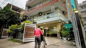 A multi-story residential building with a gated entrance, potted plants, and a visible staircase leading to the upper floors. - Parfait Street 3Bhk Service Apartment Near Fortis (Gurugram)