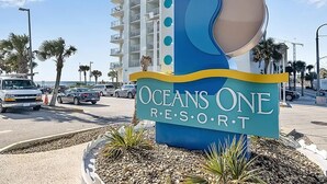 Ein Schild für das Oceans One Resort, modern gestaltet mit einem Wellenmuster und dem Namen des Resorts.