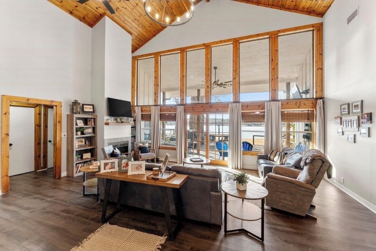 A spacious living room with a large window, a wooden ceiling, and a cozy seating area.