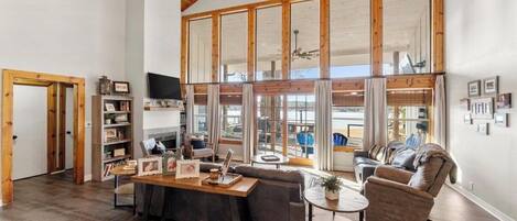 A spacious living room with a large window, a wooden ceiling, and a cozy seating area.