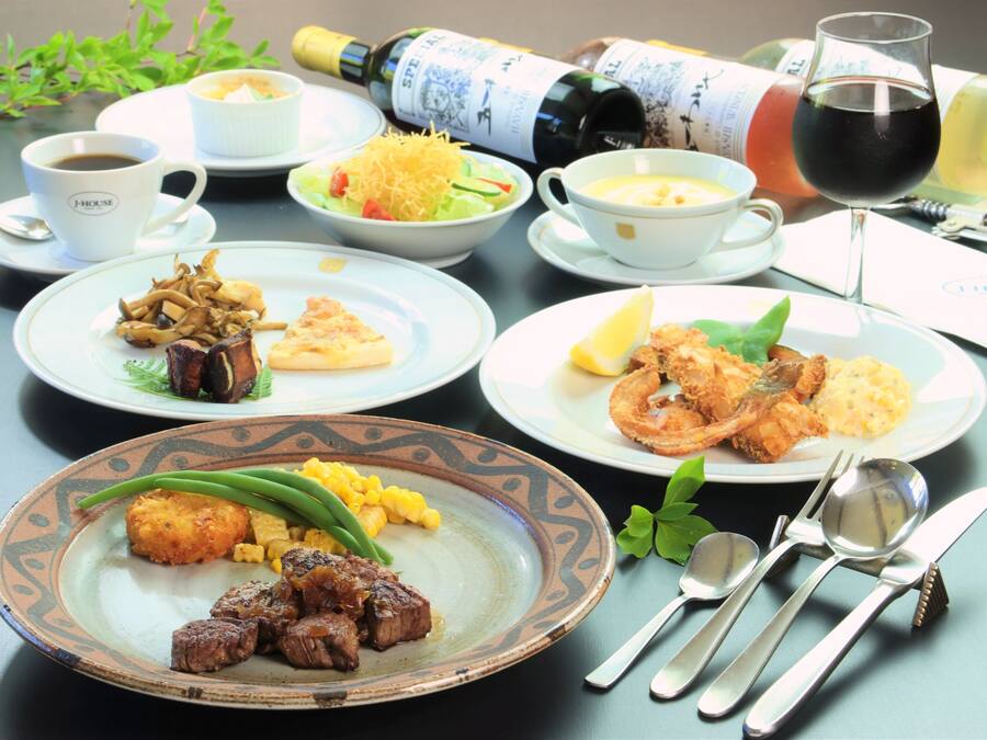 A table set with various dishes, a bottle of wine, and a glass of red wine.