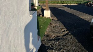 Ein Gebäude mit einer Pergola, Blick auf das Meer und einer Schotterauffahrt.