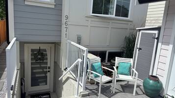 A residential entryway with a door, steps, and a small outdoor seating area with chairs.