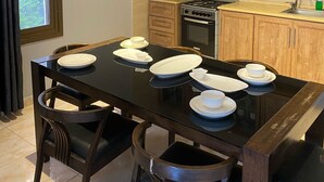 A modern kitchen with wooden cabinets, a gas stove, and a dining table set with plates and cups. - San Vito chalet (Sweimeh)