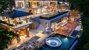 A multi-story modern house with a large outdoor pool, multiple seating areas, and a well-lit patio. - The Aquila Villa  (Kamala)
