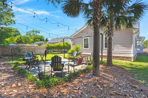 A residential backyard with a patio area, outdoor furniture, and a house.