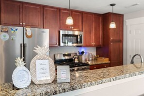 A modern kitchen with wooden cabinets, stainless steel appliances, and granite countertops.