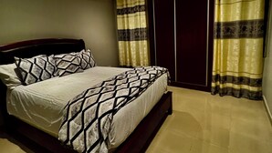 Un dormitorio con cama, cortinas, ventilador de techo y armario.