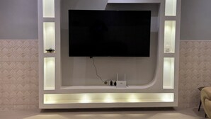 Una pared moderna con un televisor de pantalla plana, iluminación integrada y un panel de control.