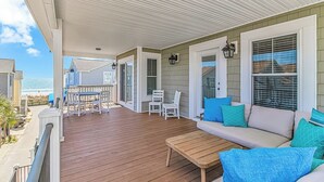 A covered outdoor deck with a wooden floor, white furniture, and a view of the ocean. - Ocean Views! 5BR Beach House Steps to Beach! (Myrtle Beach)
