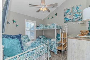 A room with bunk beds, a ceiling fan, and wall art. - Ocean Views! 5BR Beach House Steps to Beach! (Myrtle Beach)
