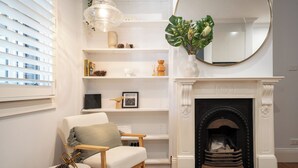A living room with a white fireplace, a round mirror, and a bookshelf. - Alf and Lisa's Luxury Glebe House - 2BR, 2BA With Free Lockup Parking (Glebe)