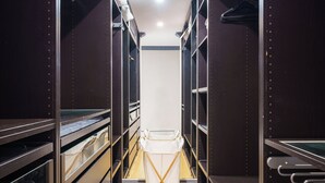 A narrow walk-in closet with metal shelving and a central folding chair. - Alf and Lisa's Luxury Glebe House - 2BR, 2BA With Free Lockup Parking (Glebe)
