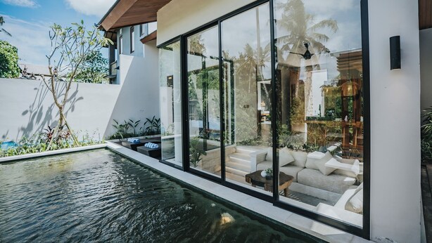 A modern house with a glass-enclosed patio, a swimming pool, and outdoor furniture. - Villa Manna Ubud (Ubud)