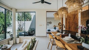 A modern kitchen with wooden cabinets, a dining table set with plates and glasses, and a ceiling fan. - Villa Manna Ubud (Ubud)