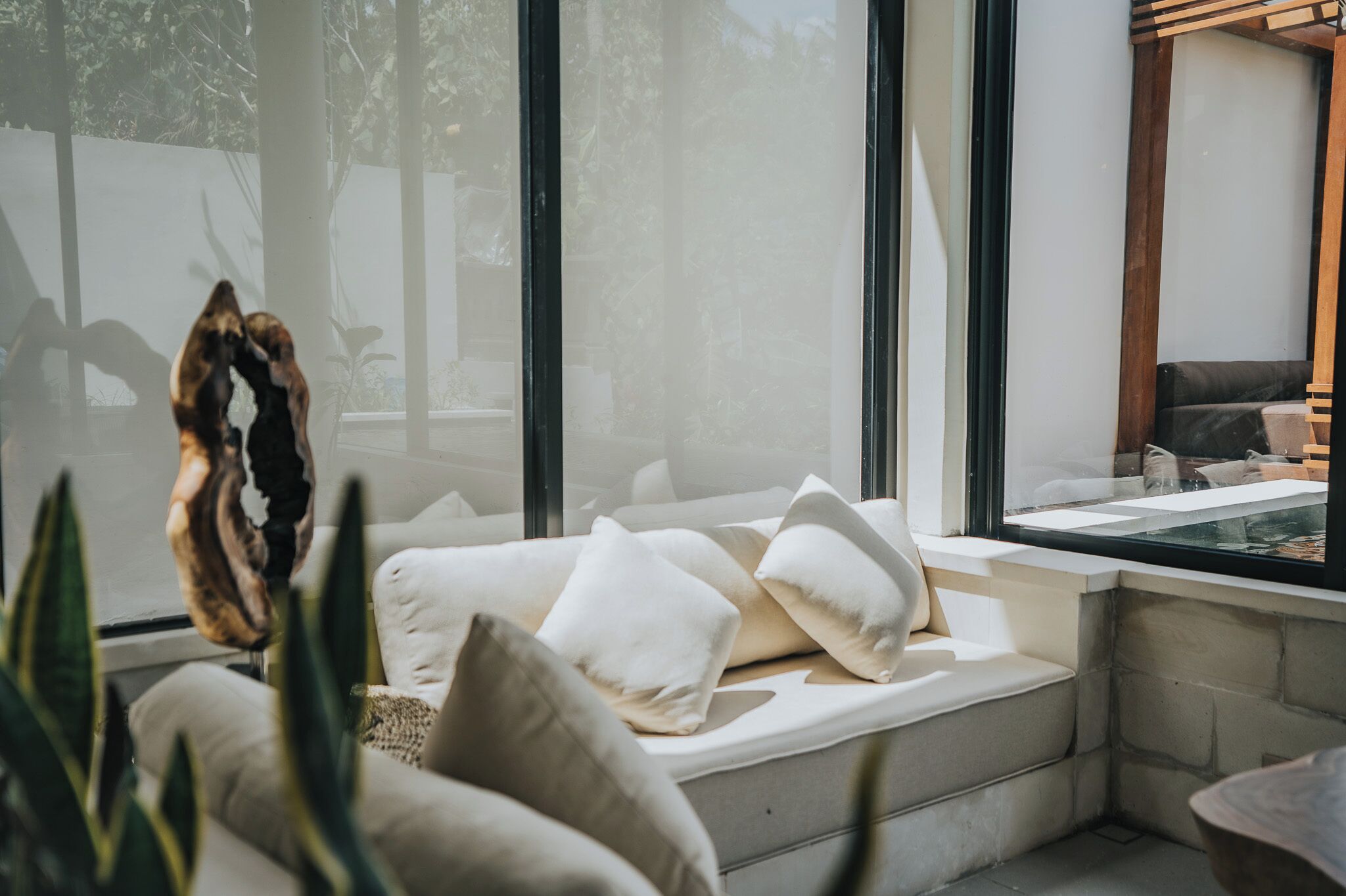 Quarto moderno com uma janela grande, um banco embutido com almofadas e vista para o exterior.