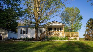 A single-story house with a porch, a tree in front, and a clear blue sky.