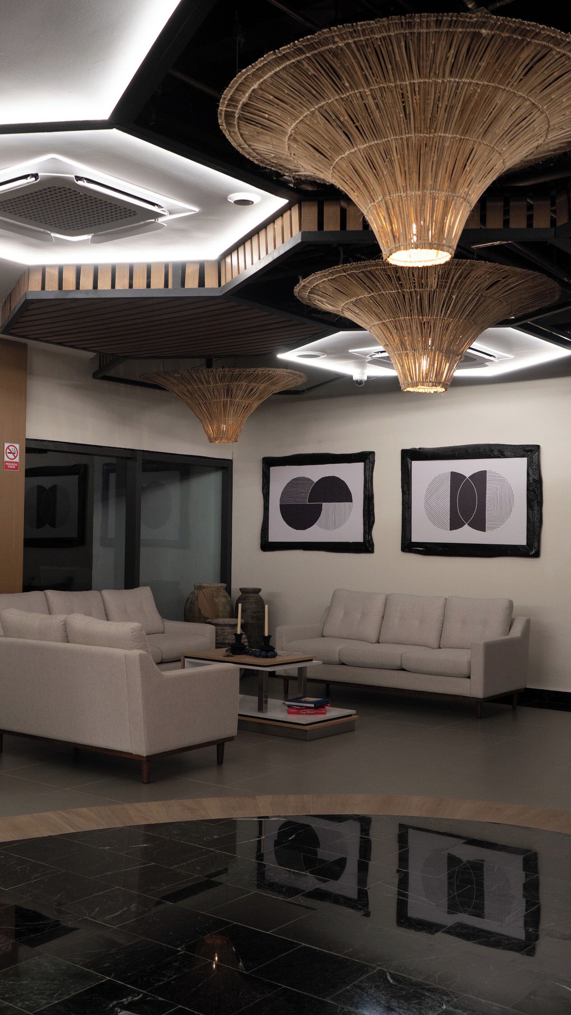 Un salon moderne avec un canapé, une table basse et deux œuvres d’art abstraites accrochées au mur.