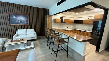 Una cocina moderna con armarios de madera, un refrigerador negro y una barra con taburetes.