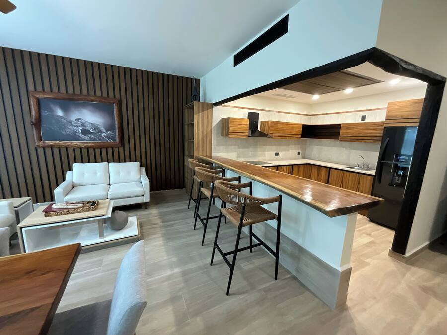 Una cocina moderna con armarios de madera, un refrigerador negro y una barra con taburetes.