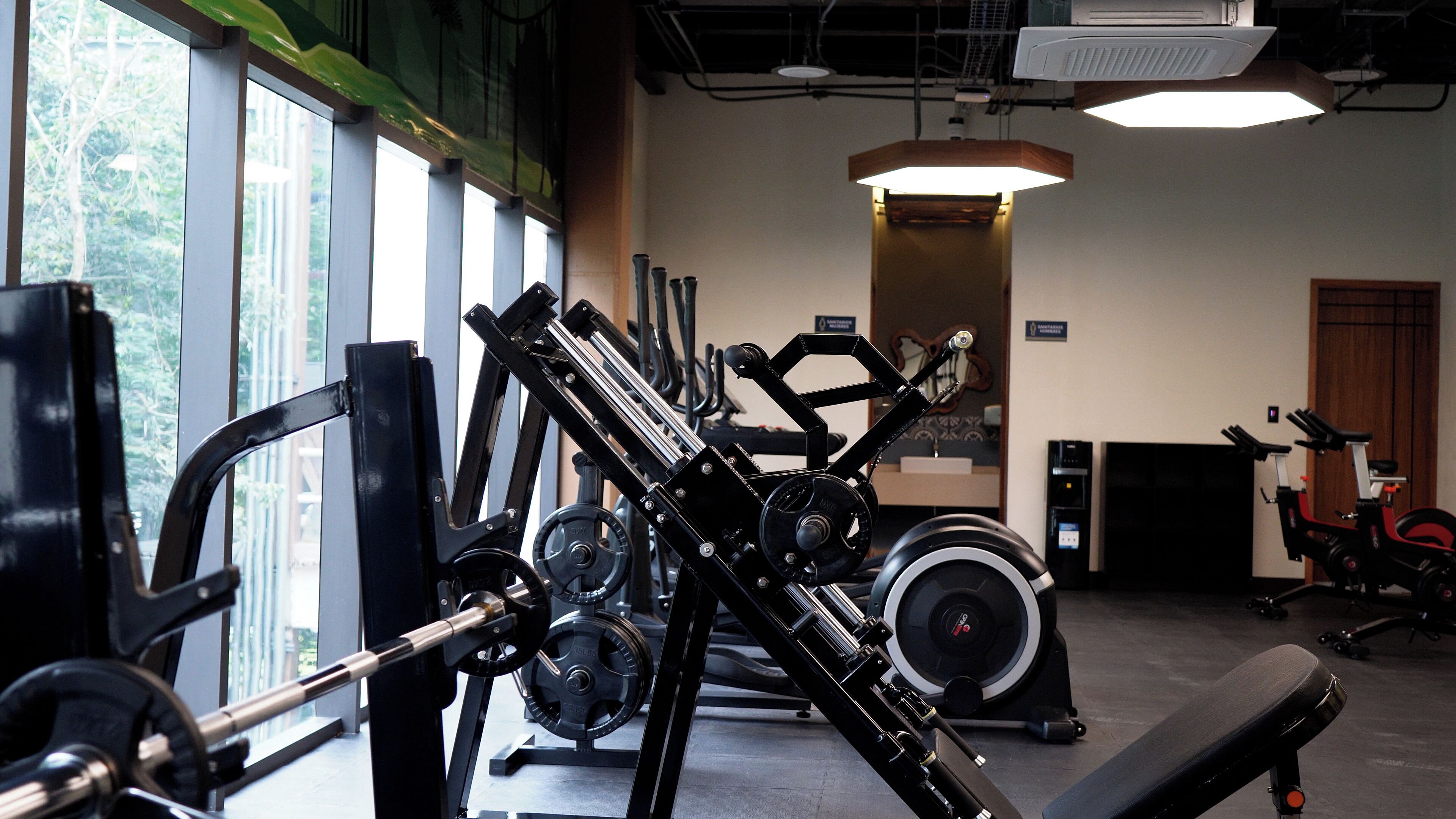 Ett gym med olika typer av träningsutrustning, inklusive styrketräningsmaskiner och en motionscykel.