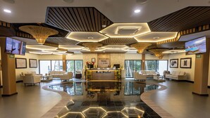 Een hotel receptie met een modern design, met een receptiebalie, een zithoek en grote ramen.