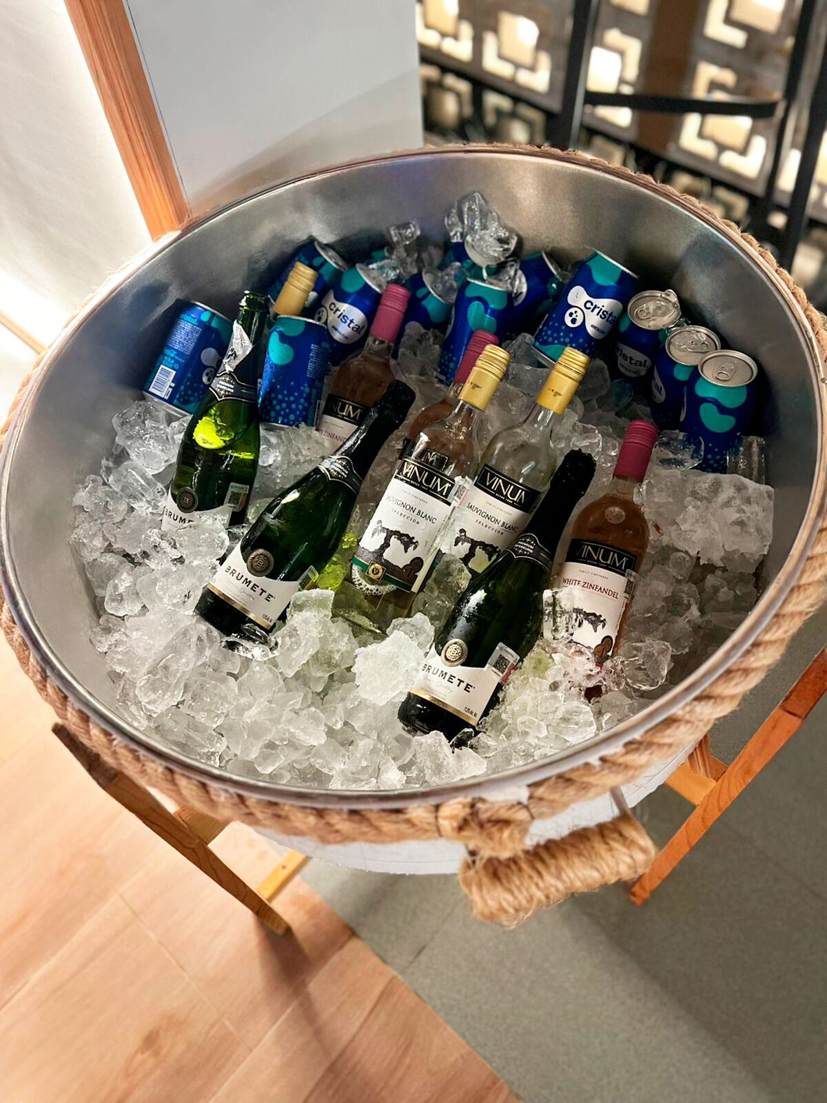 A metal bucket filled with ice, containing several bottles of wine and cans of Cristal water.