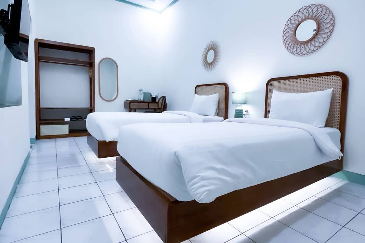A modern hotel room with a large bed, a wardrobe, a desk, and a mirror on the wall.