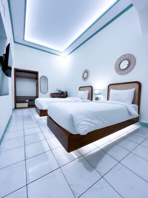 Ein modernes Hotelzimmer mit einem großen Bett, einem Kleiderschrank, einem Schreibtisch und einem Spiegel an der Wand.