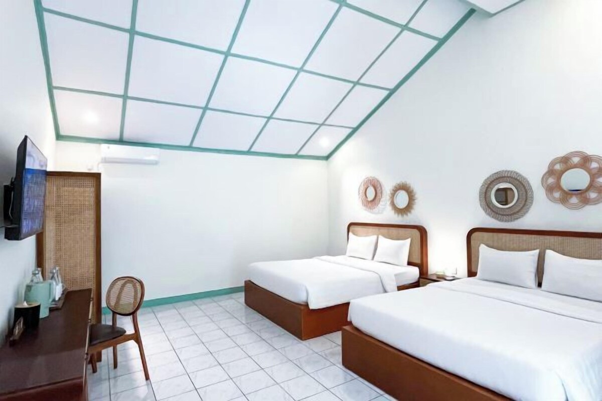 A hotel room with two beds, a dining area, and a TV.