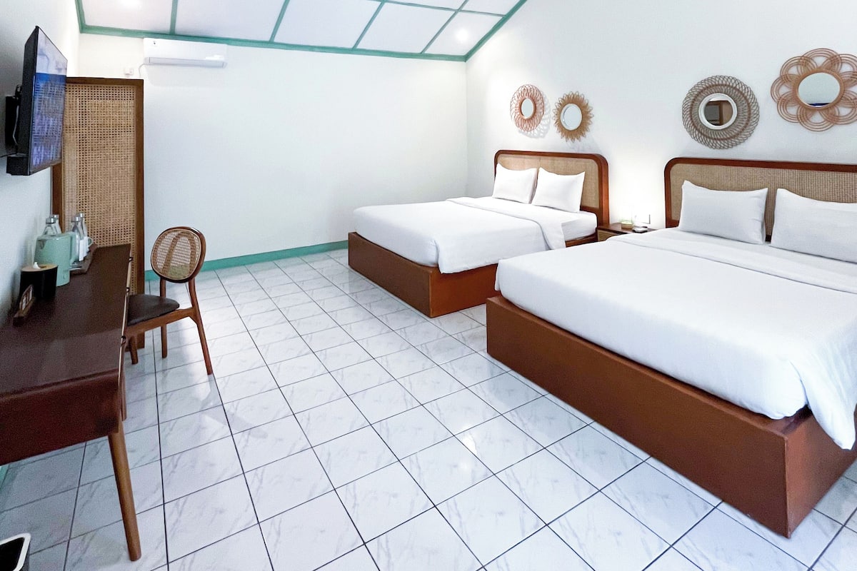 A hotel room with two beds, a desk, and a chair.