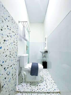 Une petite salle de bain comprenant des toilettes, un lavabo et un porte-serviettes.