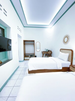 Une chambre d’hôtel avec deux lits, une télévision, une armoire, un bureau et un miroir.