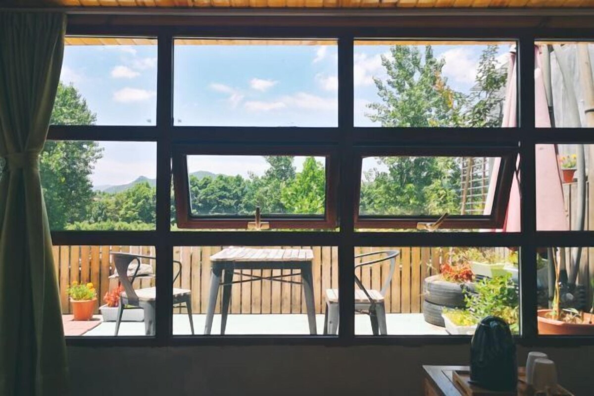 A room with a large window, a wooden table, and chairs outside.
