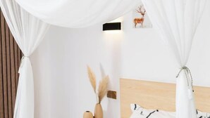 A bedroom with a wooden headboard, white curtains, a wall-mounted light, and a framed picture of a deer. - Leisurely residence (Jinyun)