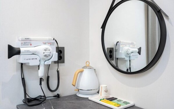 A hairdryer and a kettle on a countertop with a mirror above. - EG STAY hotel (Gwangju)