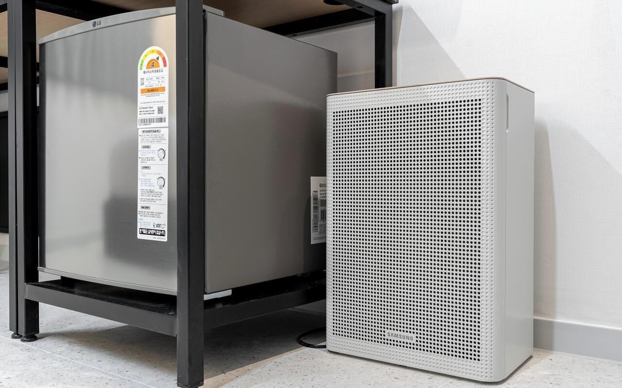 A metallic, rectangular unit with a perforated front panel, possibly a piece of equipment, next to a metal cabinet with a label.