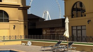 A swimming pool with lounge chairs and an umbrella, a Ferris wheel in the background, and a building with a sign that reads "Odyssey Nurturing Imaginative Young Minds". - Large 5br, Sea & JBR view, Easy Beach Access, Family Friendly! (Dubai)