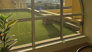 A room with a large arched window overlooking a grassy area and a Ferris wheel. - Large 5br, Sea & JBR view, Easy Beach Access, Family Friendly! (Dubai)
