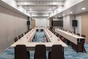 A conference room with a long table, chairs, and a projector screen.