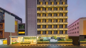 A modern hotel with multiple floors, balconies, and a well-lit entrance. - Unisi Hotel Malioboro (Yogyakarta)