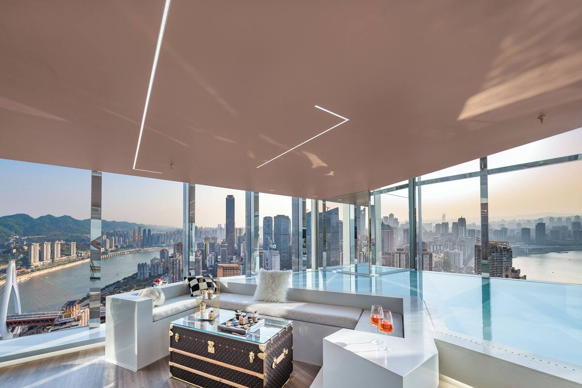 A modern living room with a glass floor overlooking a cityscape and river.