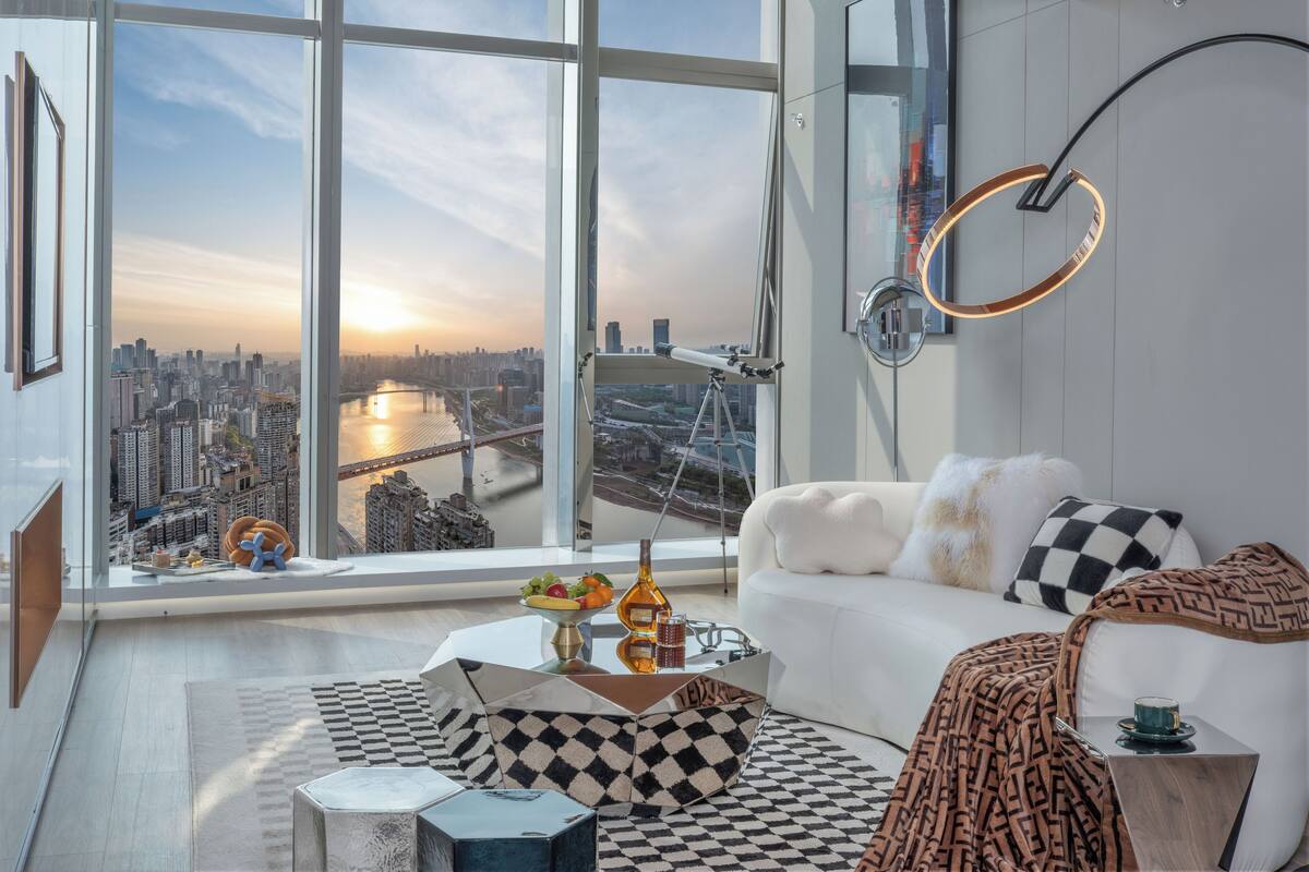 A modern living room with a large window overlooking a cityscape and a river.