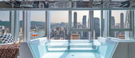 A high-rise room with a large skylight, city views, and a checkered pillow on the bed.