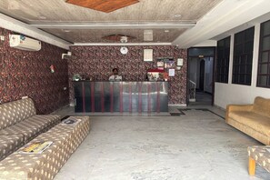 Un espace d’accueil avec un mur décoré de motifs, un comptoir d’accueil, un canapé et un divan.